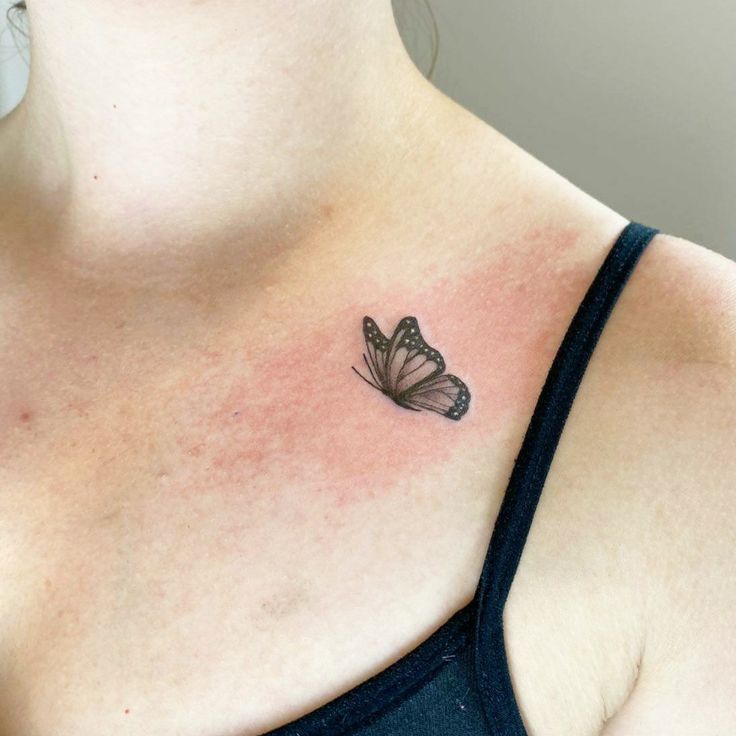 a woman's chest with a small butterfly tattoo on the left side of her chest