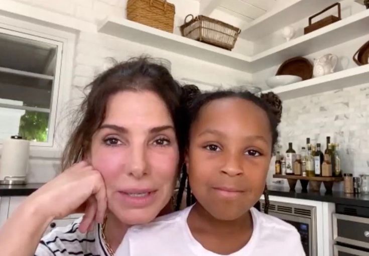 a woman standing next to a child in a kitchen