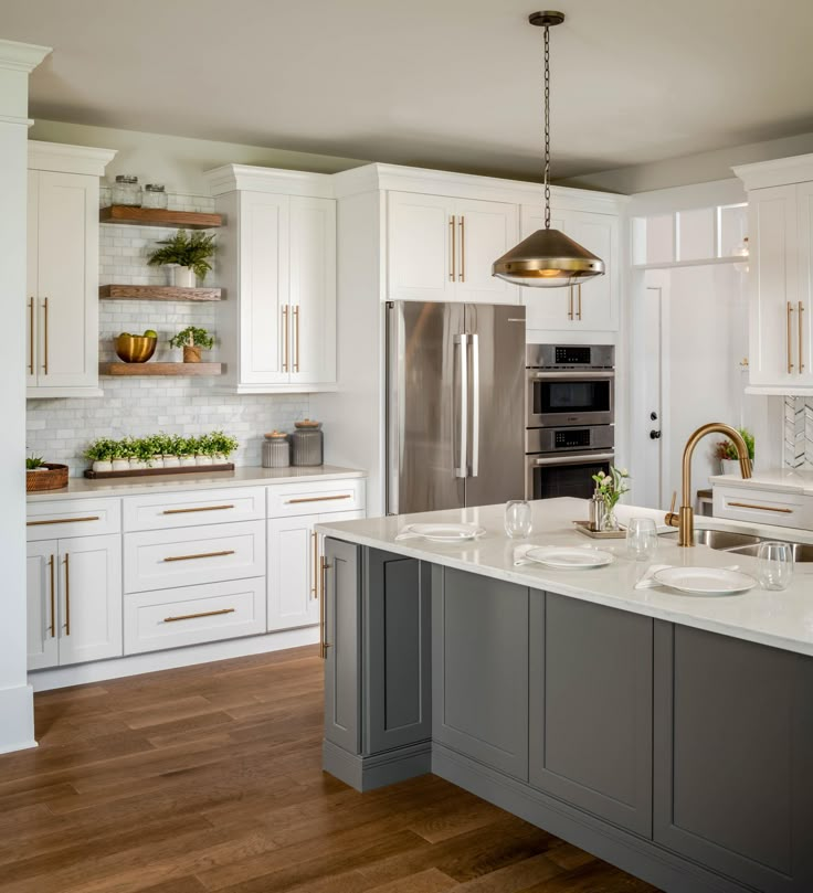 a large kitchen with white cabinets and stainless steel appliances, including an island in the center