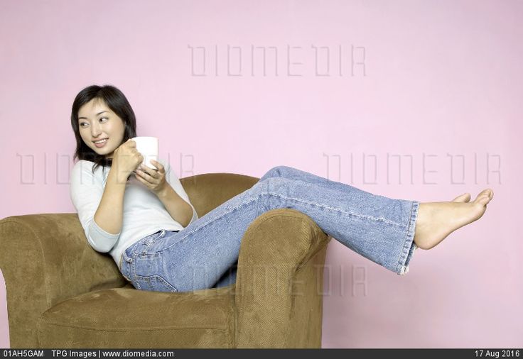 a woman sitting on top of a brown chair holding a remote control in her hand