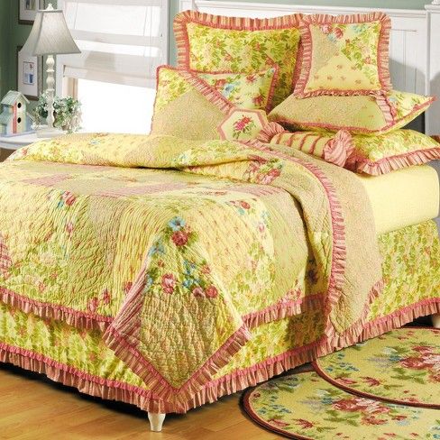 a bed with yellow and pink bedspread in a room