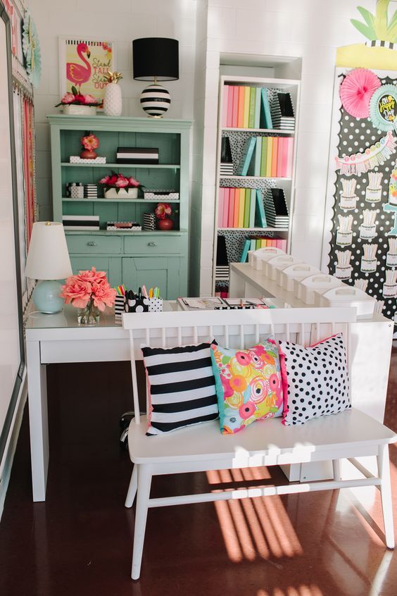 a white bench sitting in front of a desk with lots of pillows on top of it