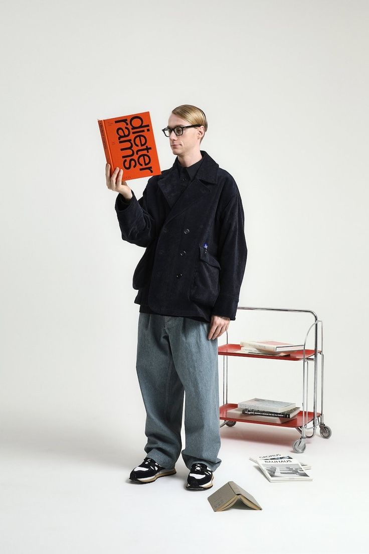 a man standing in front of a cart holding an orange book