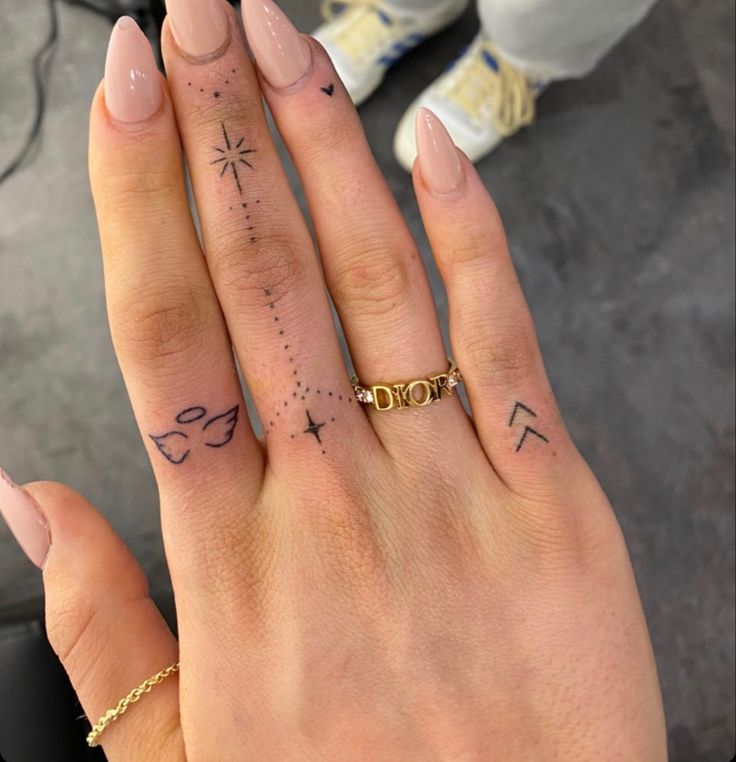 a woman's hand with tattoos on it and a gold band around her finger