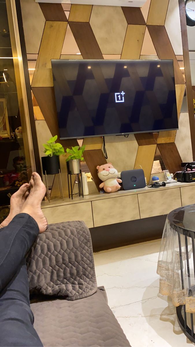 a person sitting on a couch in front of a flat screen tv mounted to the wall