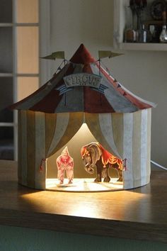 an illuminated circus tent with elephants and clowns on the front, sitting on top of a table