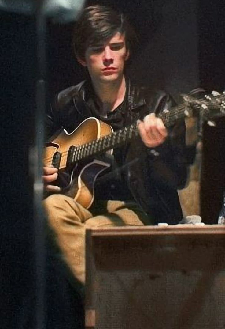 a young man is playing an acoustic guitar