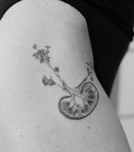 a woman's thigh with an orange slice and flower tattoo on the side of her leg