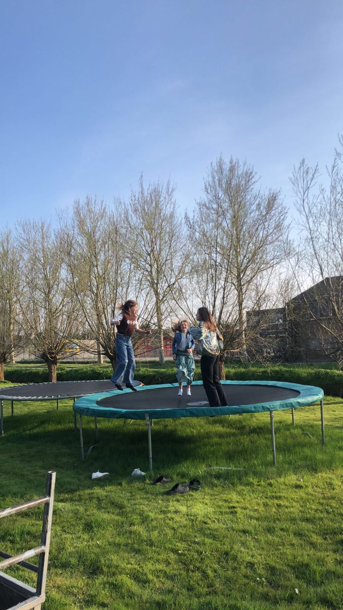 two children jumping on a trampoline in the grass