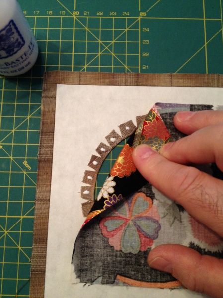 someone is cutting out some fabric on a piece of crafting paper with scissors and glue