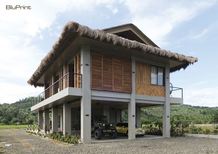 a car is parked in front of a house with a thatched roof and balcony