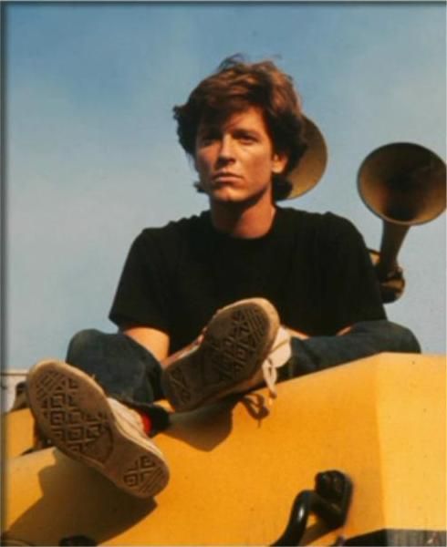 a young man sitting on top of a yellow vehicle with his feet propped up in the air