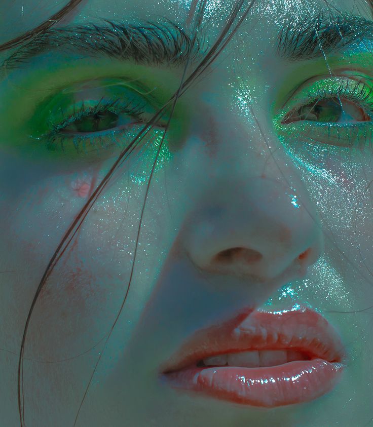 a woman's face is covered in green and blue glitters as she poses for the camera