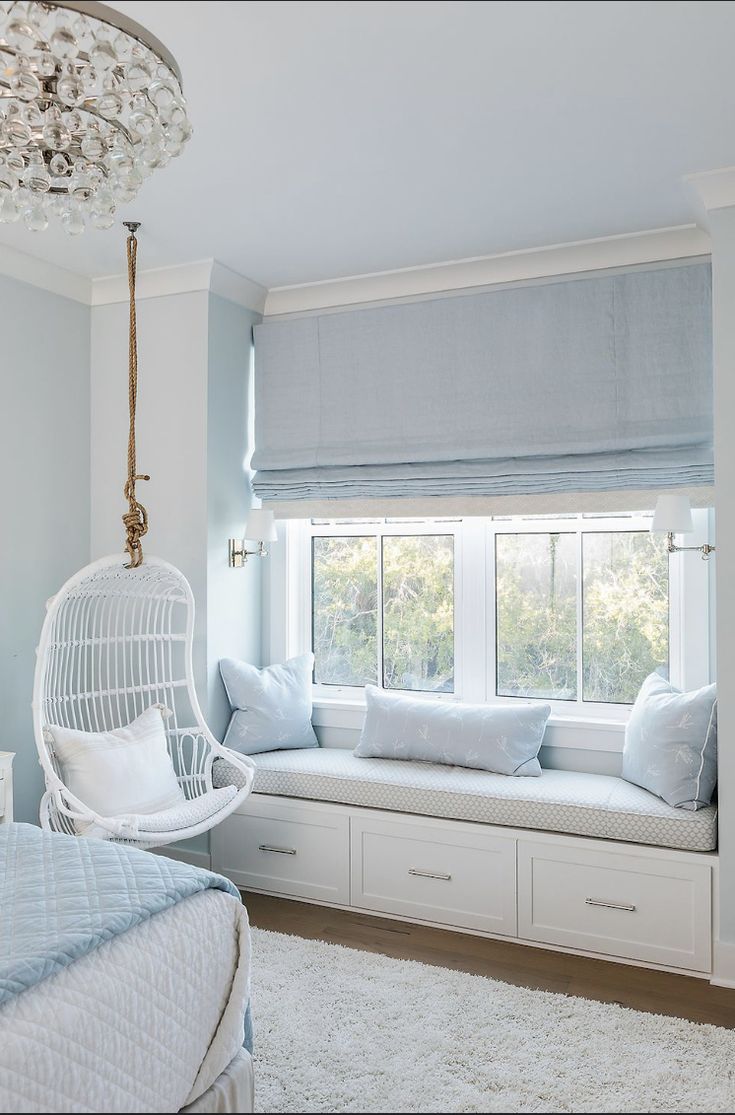 a bedroom with white furniture and blue curtains on the window sill, along with a hanging swing chair