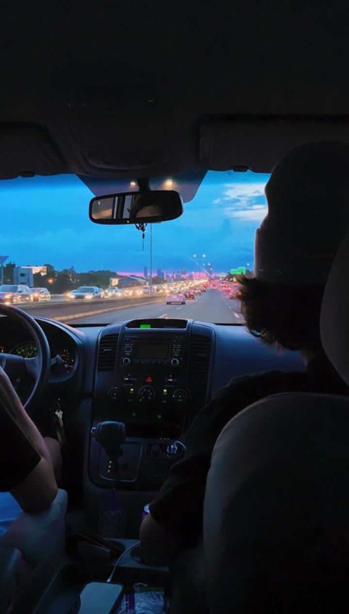 two people in the passenger seat of a car driving down a highway at night time