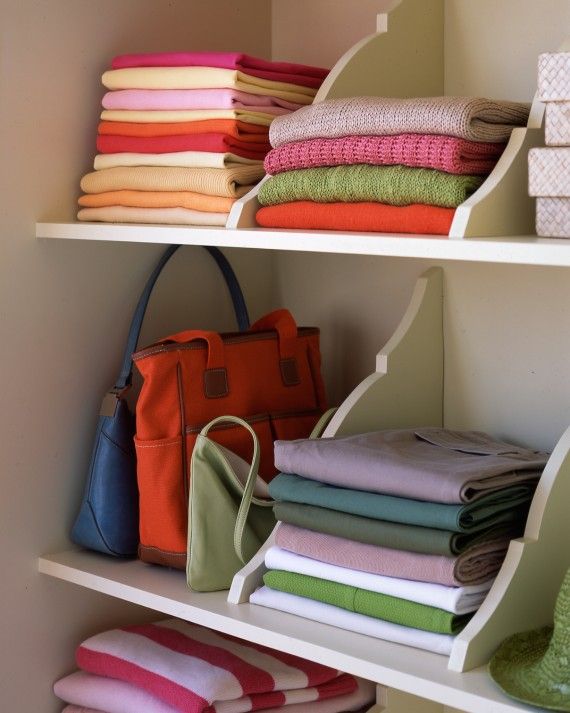 an open shelf with many folded towels and purses