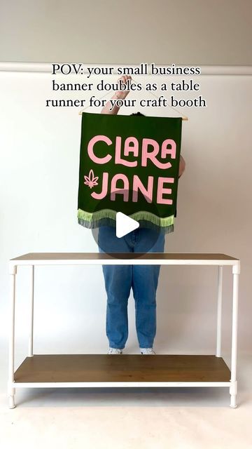 a person holding up a sign with the words clara jane written in pink on it