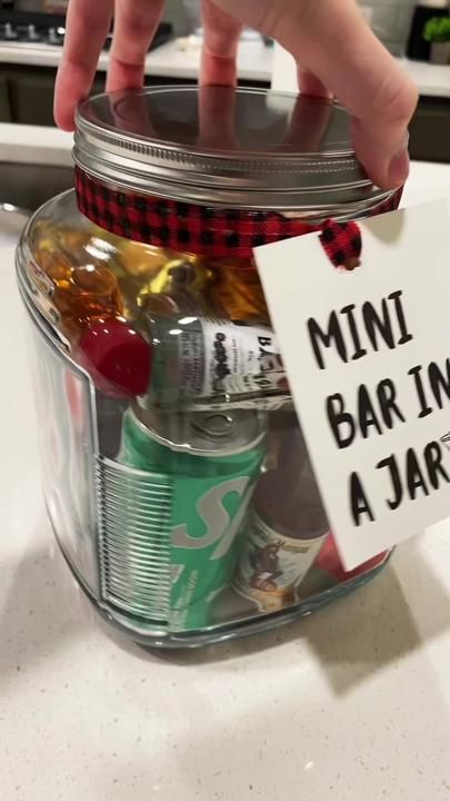 a person holding a mini bar in a jar with a sign on it that says mini bar in a jar