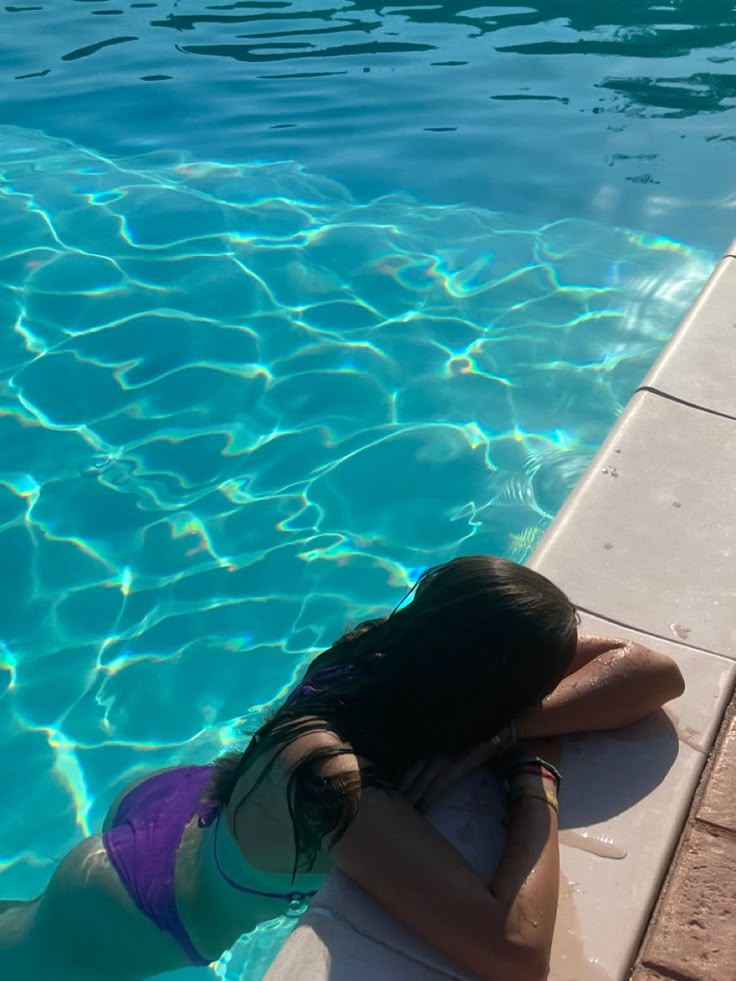 a woman laying on the edge of a swimming pool