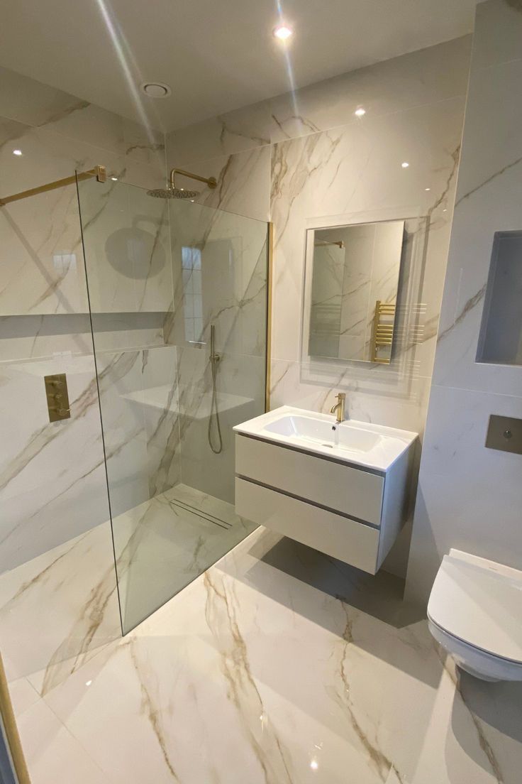 a bathroom with a glass shower door, sink and toilet