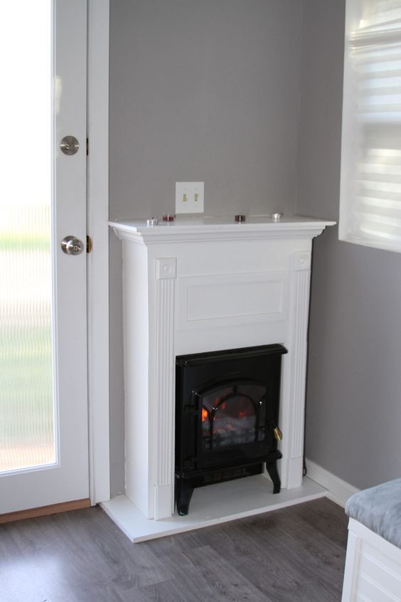 a fire place in the corner of a room with a door open to another room