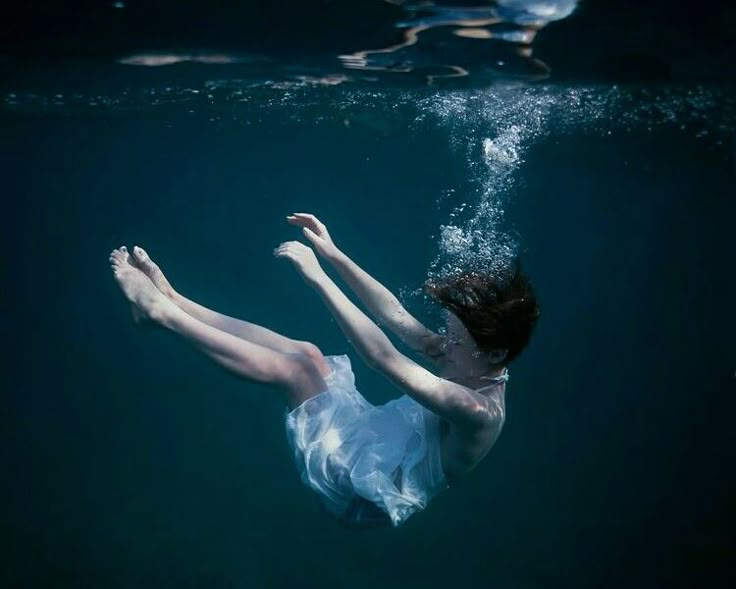 a woman is floating in the water with her arms spread out and feet up above the water