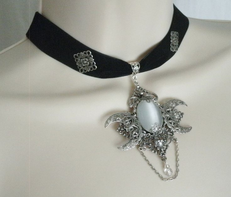 "Gothic Choker Necklace This beautiful velvet choker necklace has a silver plated crescent moon pendant with white catseye setting, silver plated embellishments, glass bead and silver plated chain. It is 12\" long adjustable to 17\" long. Silver plated lobster clasp." Victorian Pendant Jewelry For Evening, Elegant Vintage Charm Jewelry, Ornate Silver Jewelry With Jewels, Silver Jewels Evening Jewelry, Elegant Evening Cabochon Necklaces, Silver Jewelry With Jewels For Evening, Gothic Sterling Silver Jewelry For Parties, Silver Gothic Jewelry For Evening, Victorian Antique Silver Jewelry