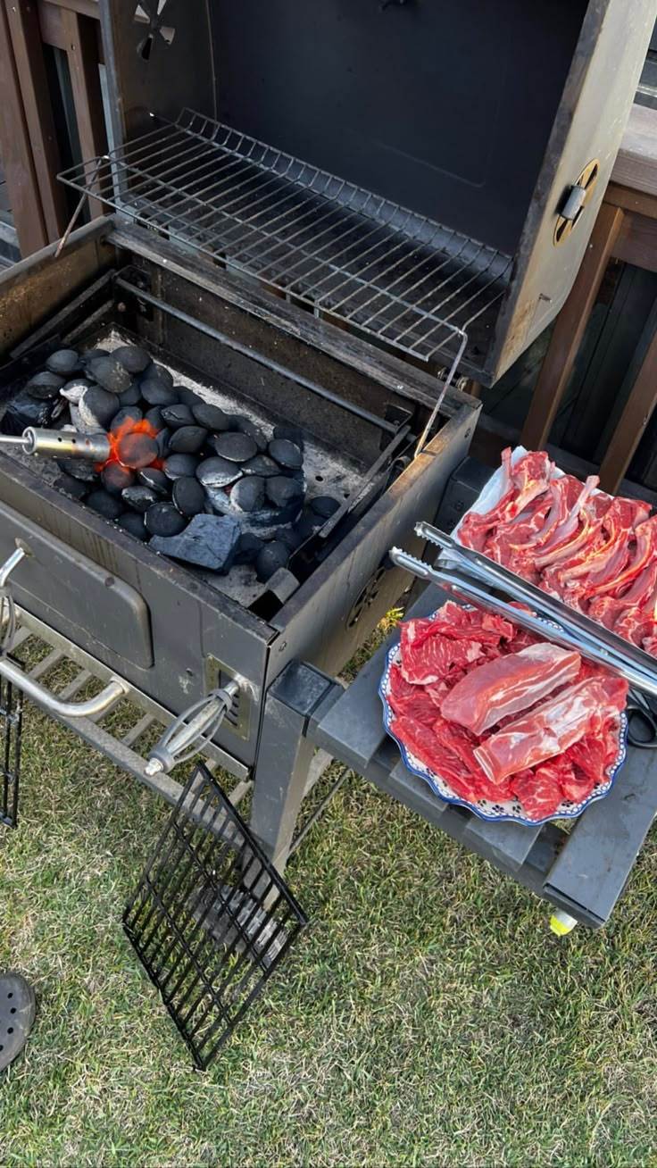 an outdoor grill with meat cooking on it