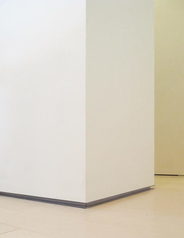 a black and white cat sitting on the floor next to a tall white box in an empty room