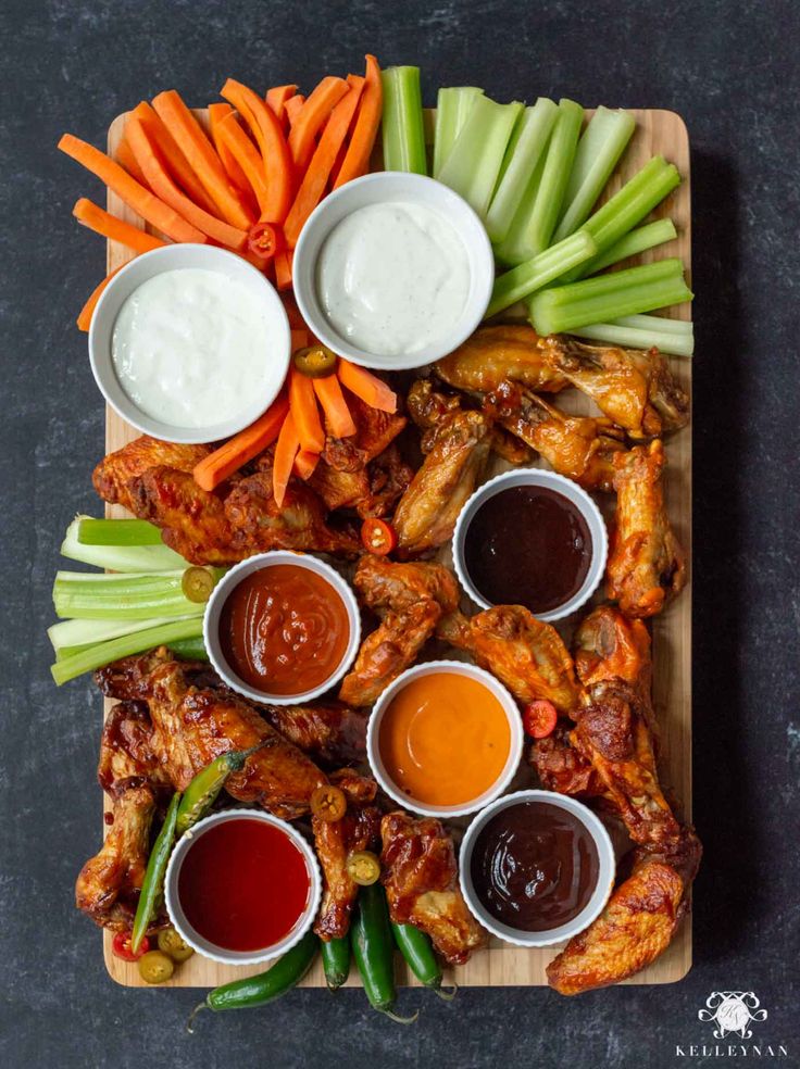 chicken wings with dipping sauces on a cutting board