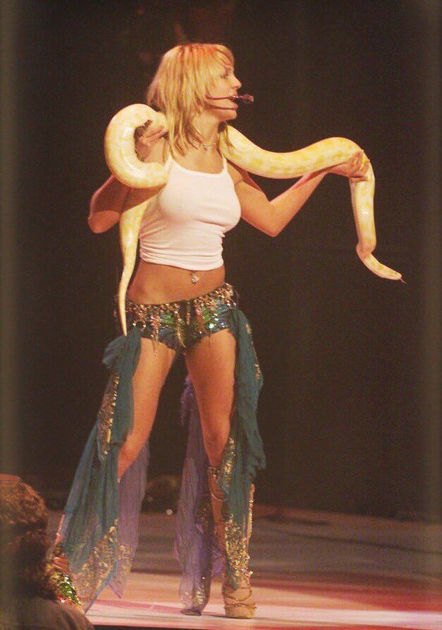 a woman holding a large snake on stage