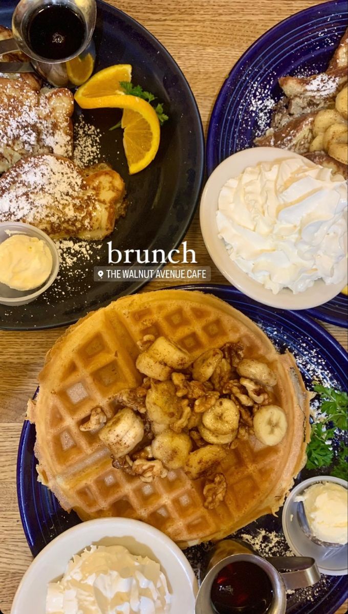 two blue plates topped with waffles covered in whipped cream and fruit next to syrup