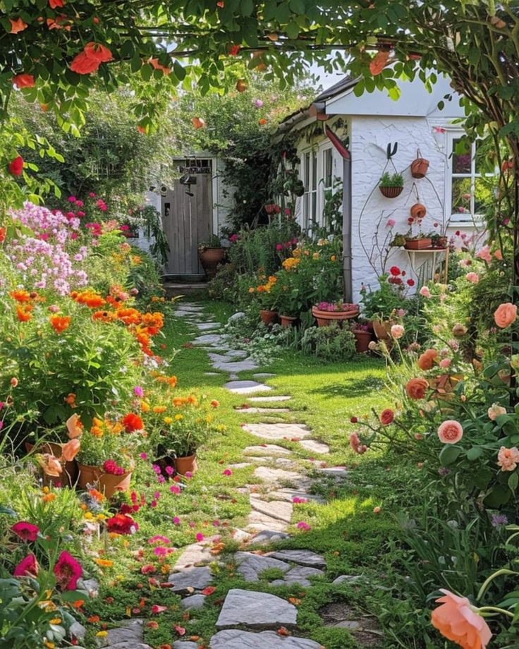 a garden with lots of flowers and plants in the front yard, along with a path leading to a shed