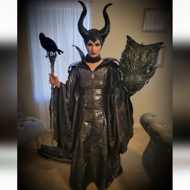 a woman dressed up as maleficent holding a bird