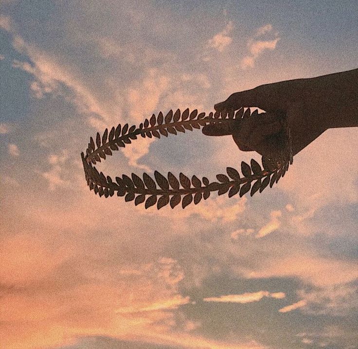 a person holding a metal object in the air with leaves on it's side