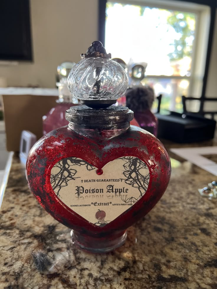 a red heart shaped bottle sitting on top of a counter