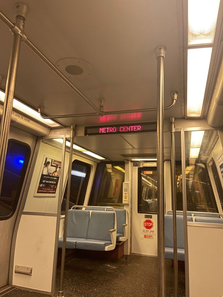 the interior of a train with blue seats and red signs on the wall above it