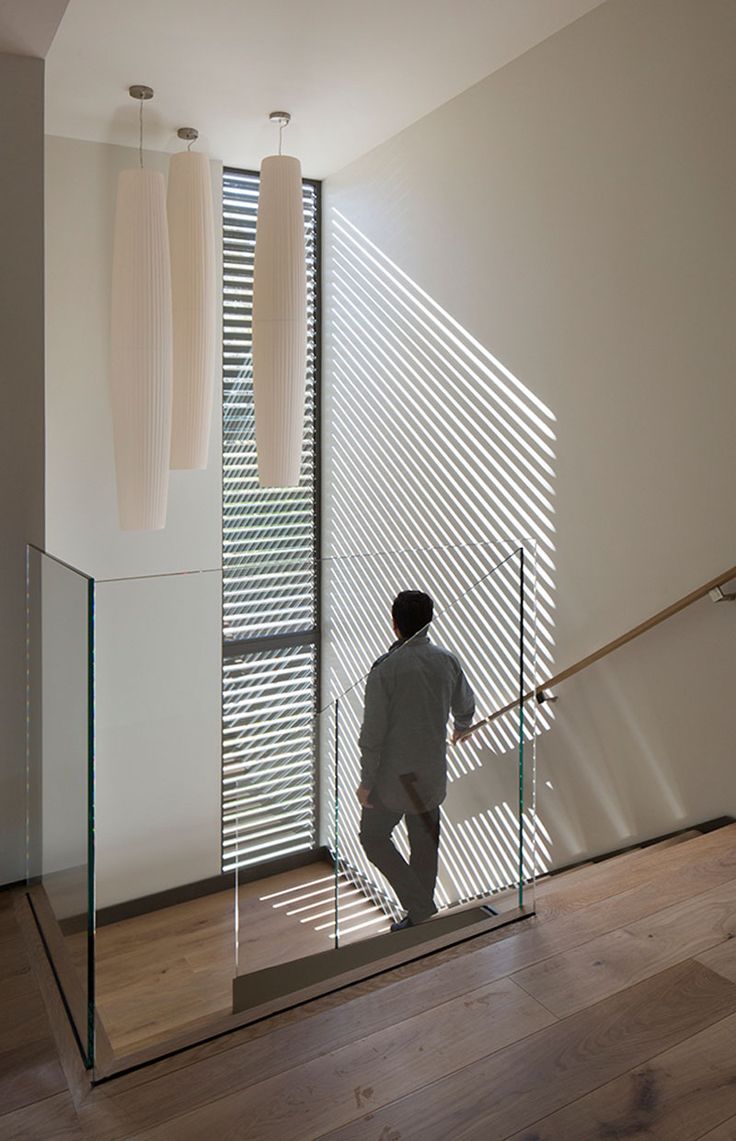 a man is walking up the stairs in front of a window with blinds on it