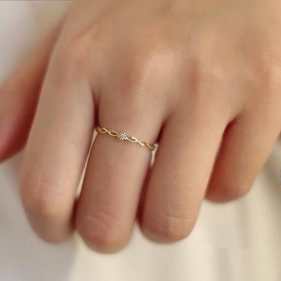 a woman's hand with a gold ring on top of her finger and a diamond in the middle