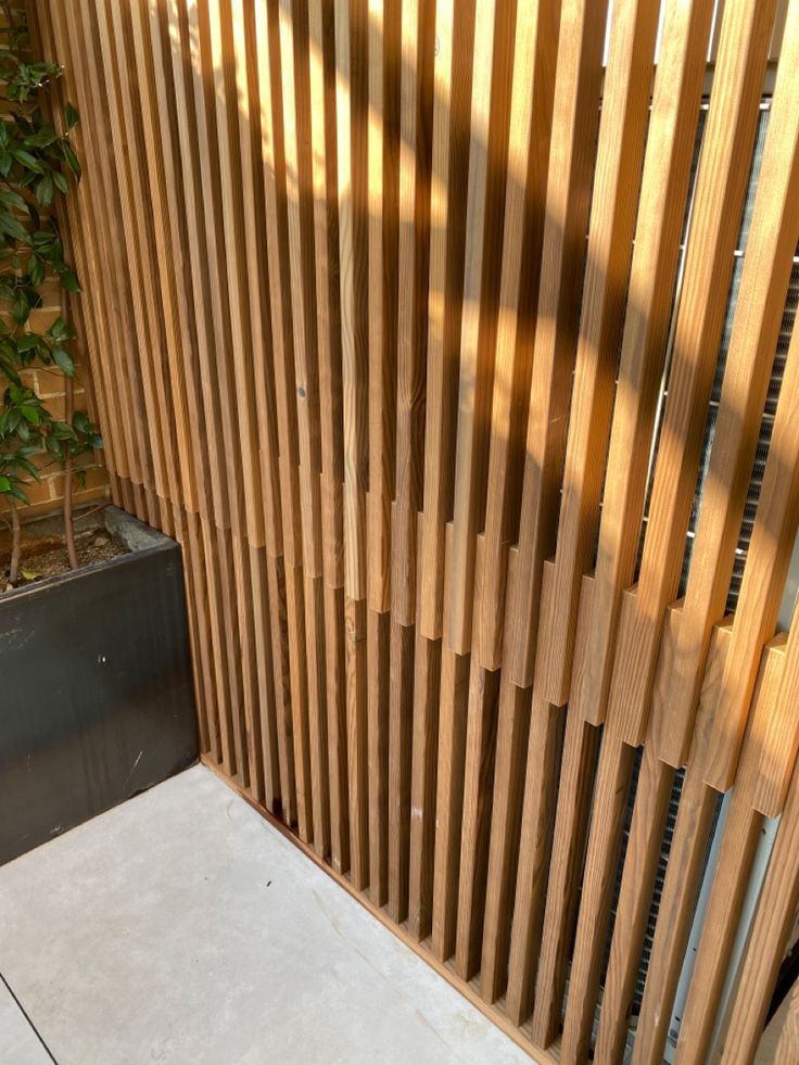 a wooden slatted wall next to a potted plant