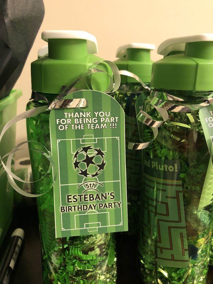 several green plastic bottles with labels on them and ribbons tied around the top one bottle is labeled, thank you for your soccer team