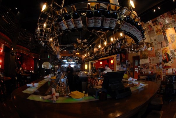 a bar with lots of bottles hanging from the ceiling