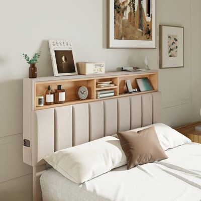 a bed with white sheets and pillows next to a painting on the wall above it