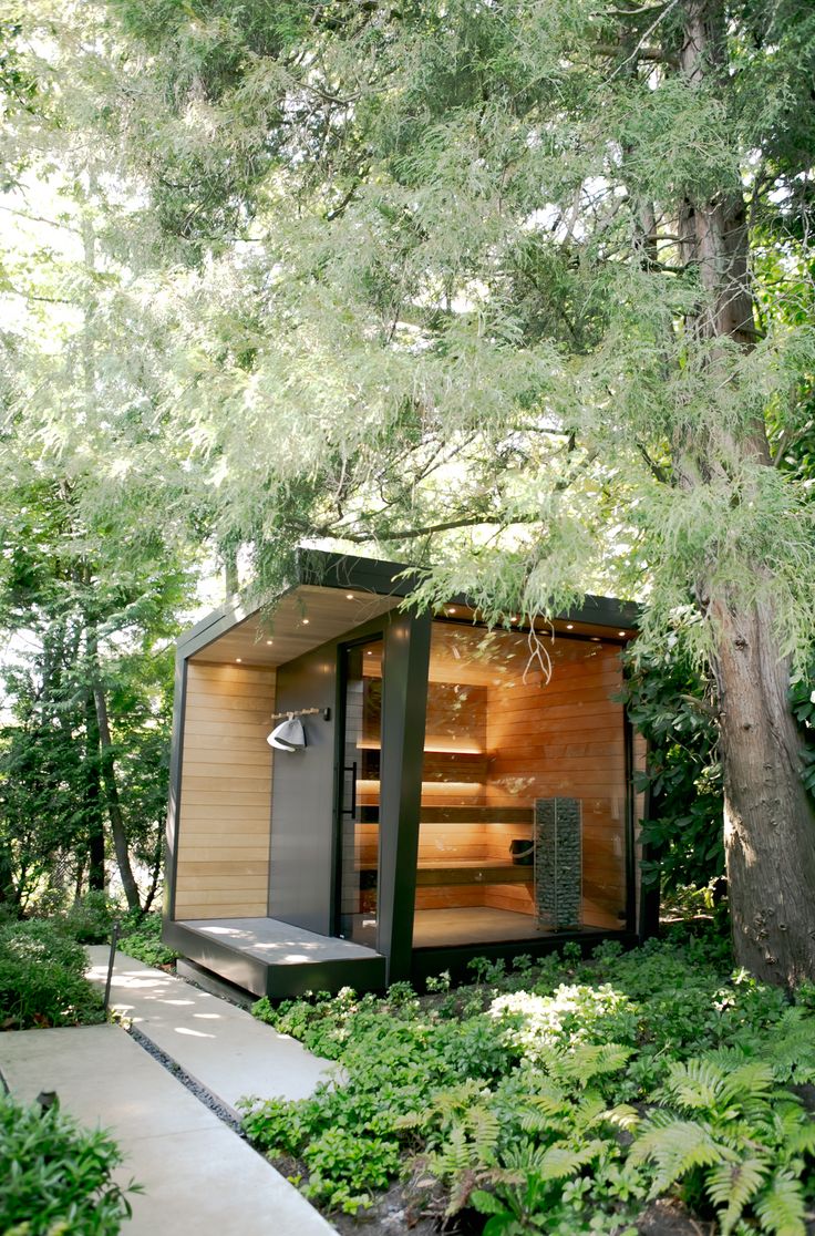 an outdoor sauna in the middle of some trees and bushes with steps leading up to it