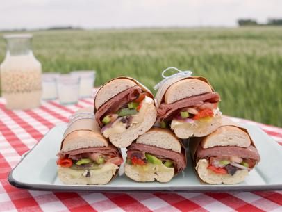 several sandwiches are on a plate with a red and white checkered tablecloth in the background