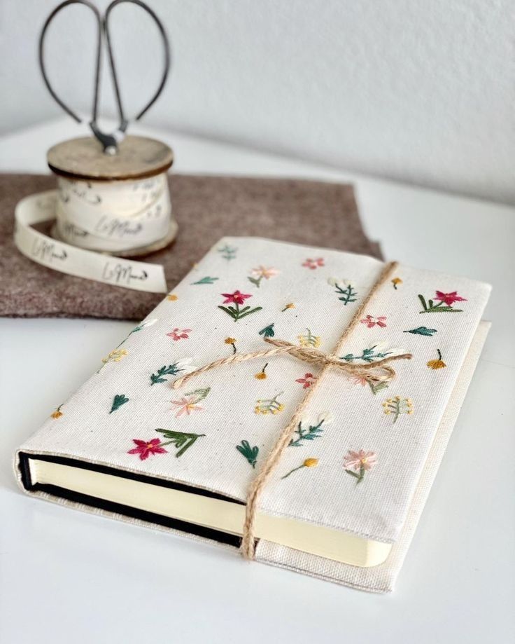 a white book sitting on top of a table next to a spool of thread