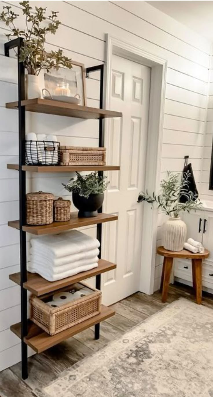 a shelf with towels and baskets on it next to a door in a white room