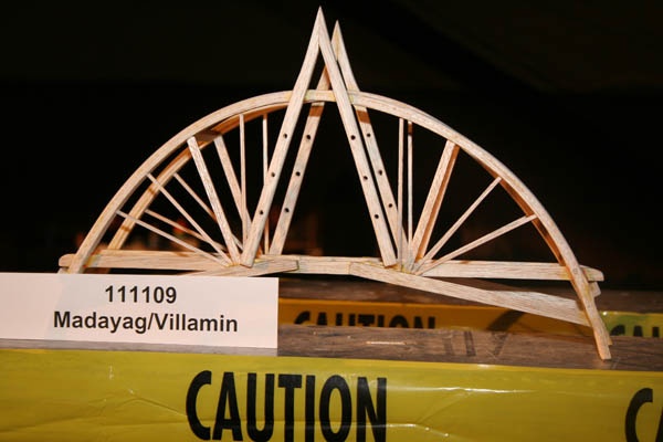 a wooden bridge is on display in a museum exhibit with caution signs below it that read 11 / 11 / 09