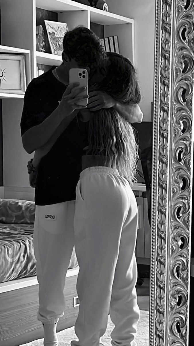 a man and woman standing in front of a mirror taking a selfie with their cell phone