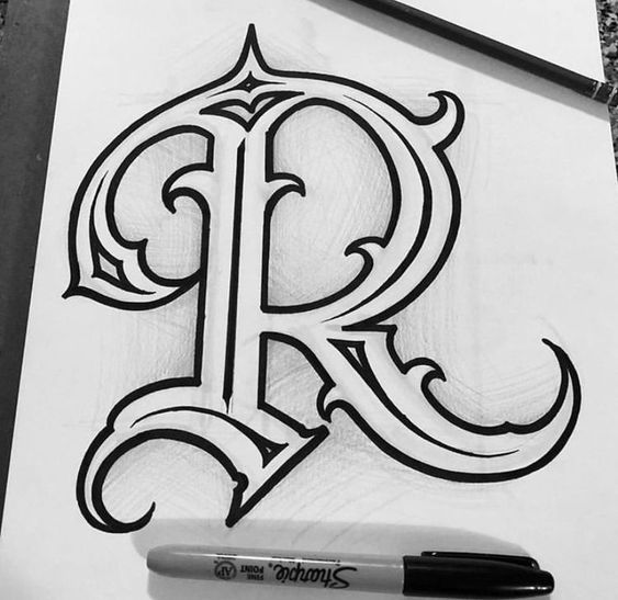 the letter r is drawn on paper with a marker and pen in front of it